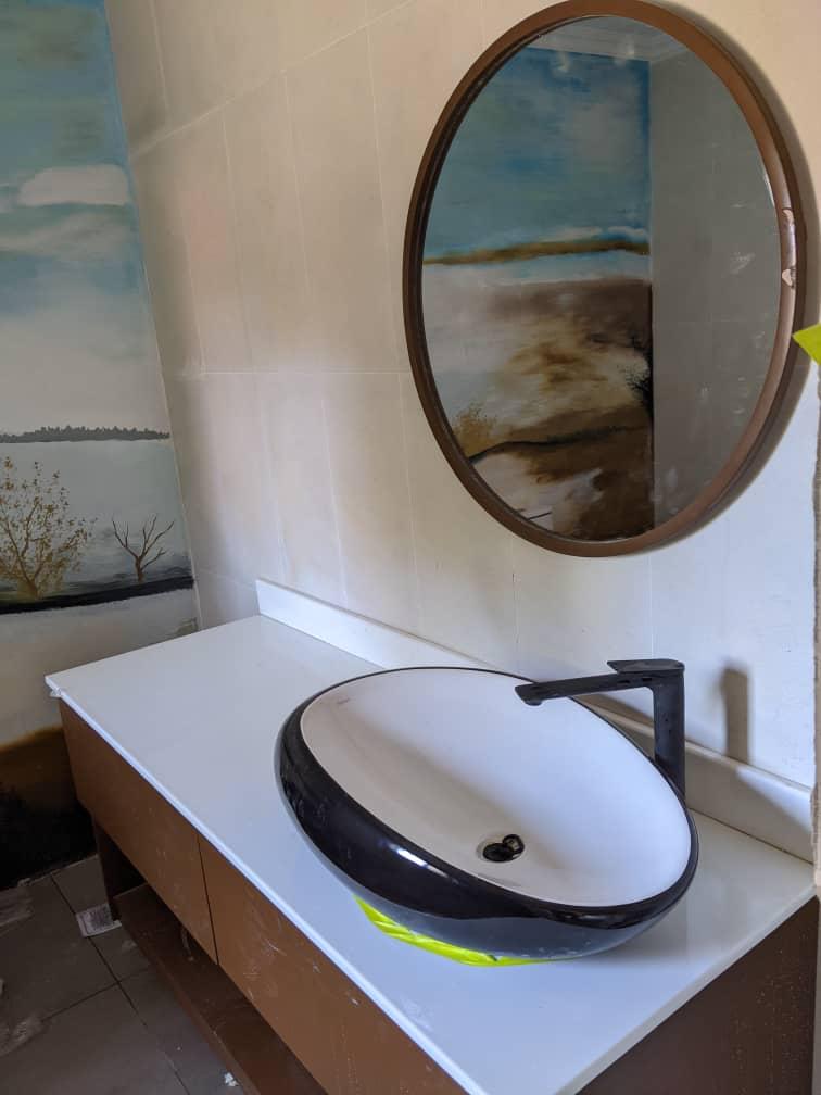 Round black and white vessel sink with circular mirror and feature wall