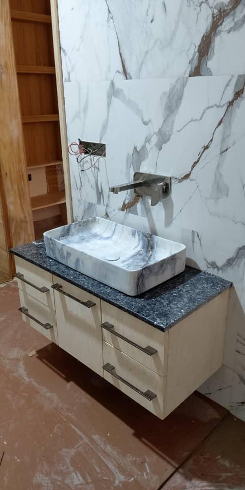 Floating vanity with marble vessel sink and marble slab wall