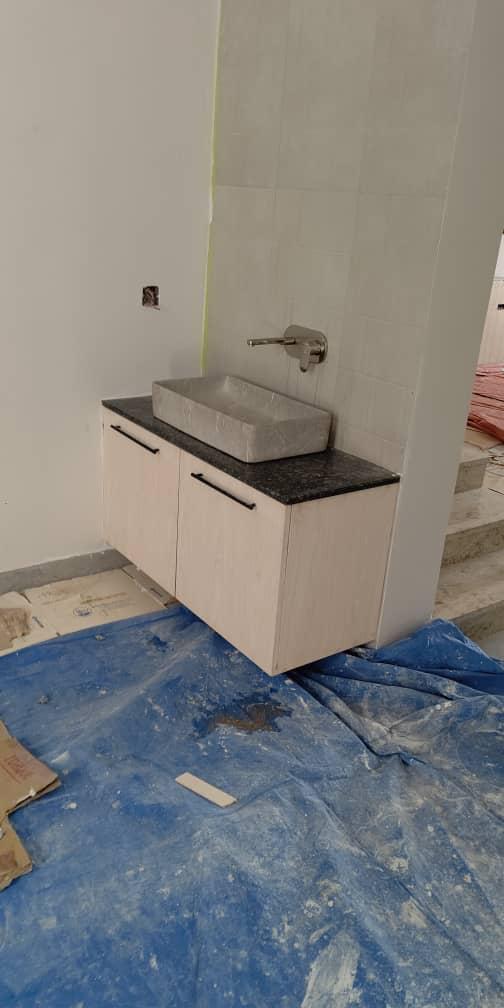 Wall-hung vanity unit with marble tiles and wall-mounted tap